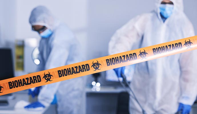 Professionals in full HAZMAT suits decontaminating a laboratory