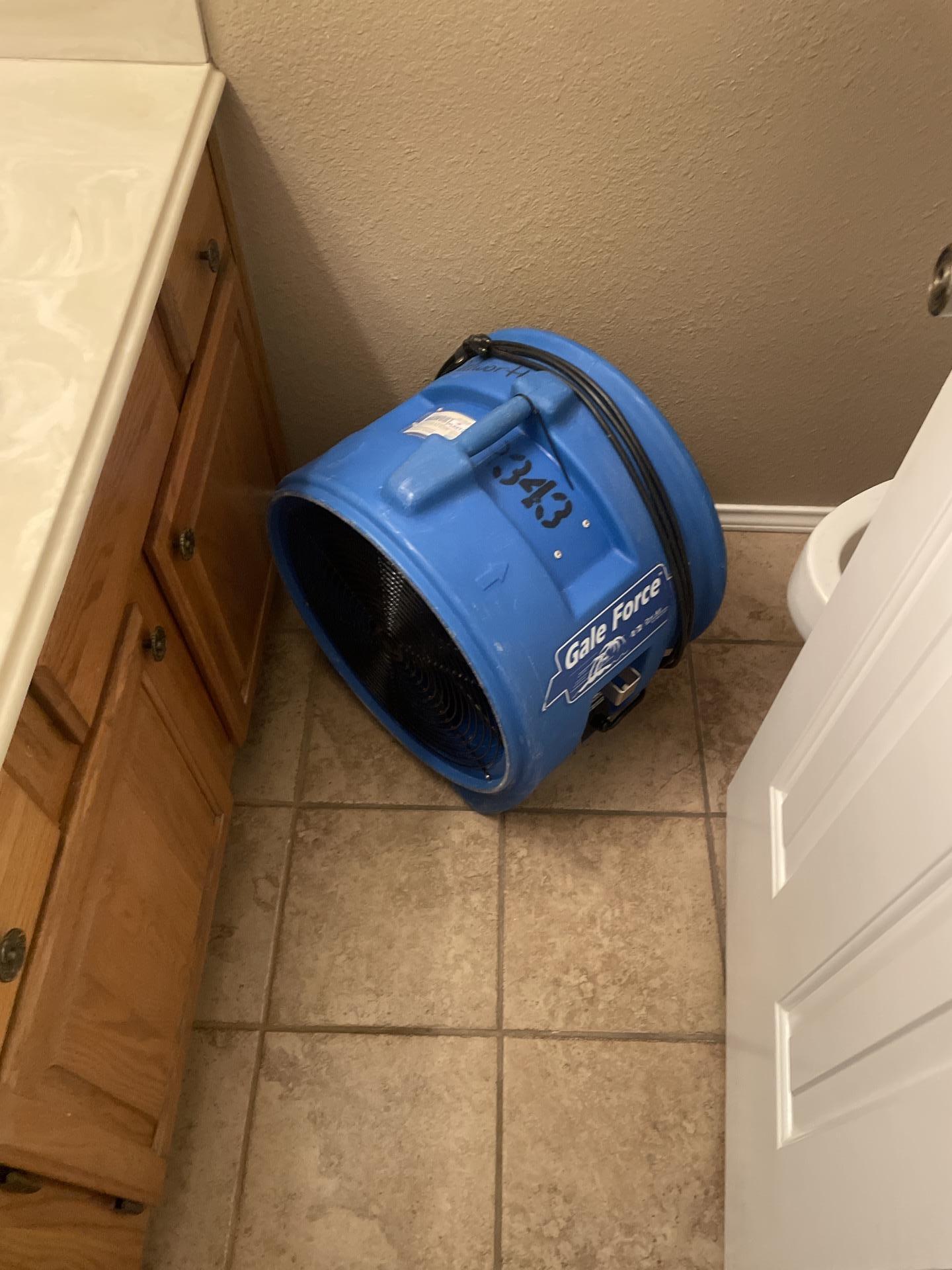 A blue Gale Force air mover placed on a tiled bathroom or utility room floor for targeted drying during water damage restoration by Dalworth Restoration.