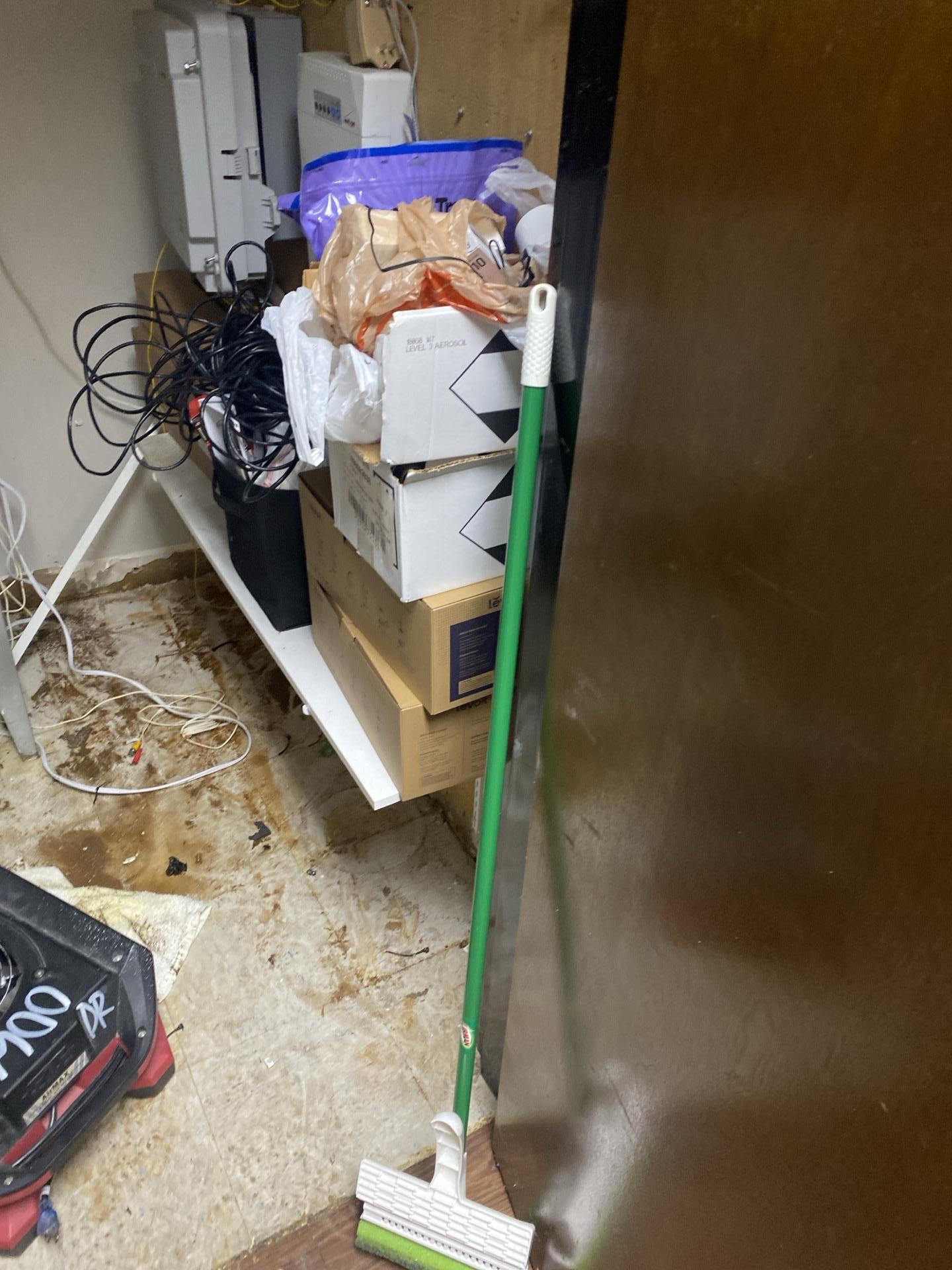 An office area featuring large printers and equipment on a carpeted floor, representing one of the commercial spaces affected by water damage.