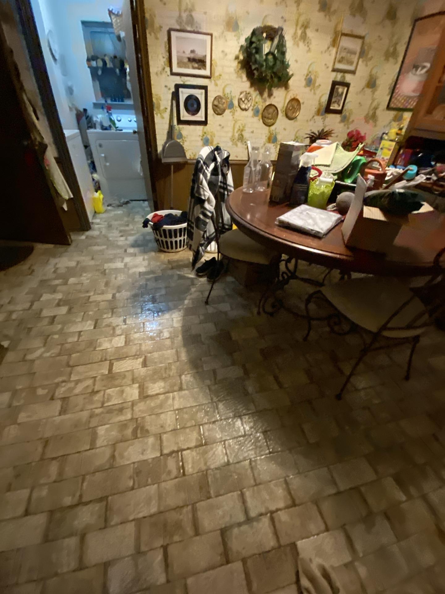 Water damaged tiled floor in a kitchen and dining area with furniture, showing the extent of water intrusion