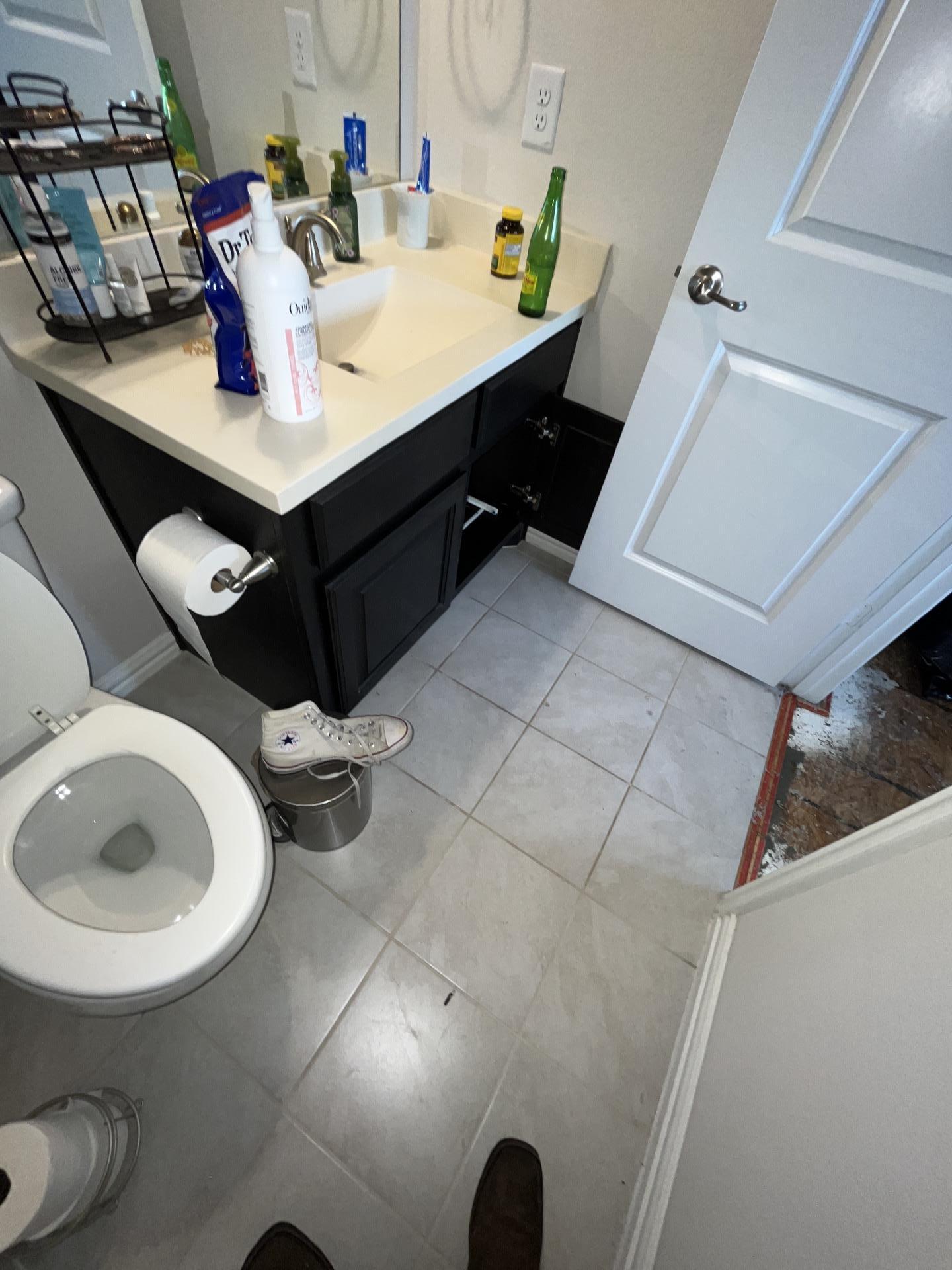 Initial water damage assessment of a bathroom vanity and tile floor in Farmers Branch, TX. This photo captures the extent of the water damage before our team began water extraction and dehumidification services for property restoration.