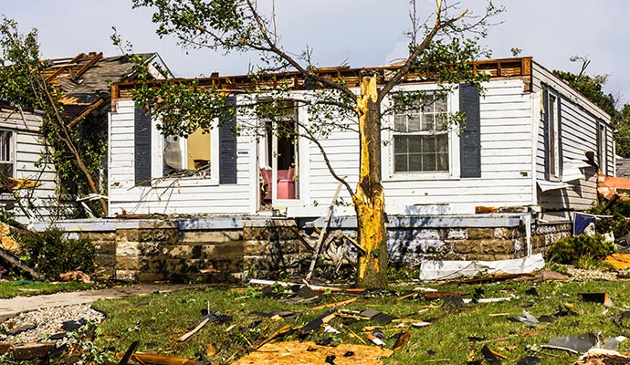Residential house affected by tropical storm with visible roof and wall damage